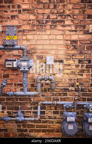 Urban Gas Meters and Pipes on Aged Brick Wall, Eye-Level View Stock Photo