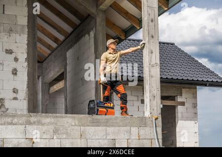 Professional construction worker standing on house side. Stock Photo