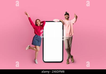 Two Happy Friends Posing Next to a Large Smartphone Stock Photo