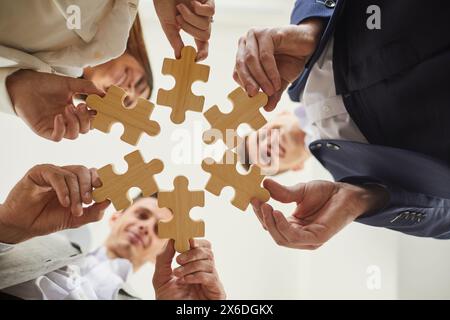 Business colleagues holding puzzles as symbol of cooperation, brainstorming and teamwork. Stock Photo