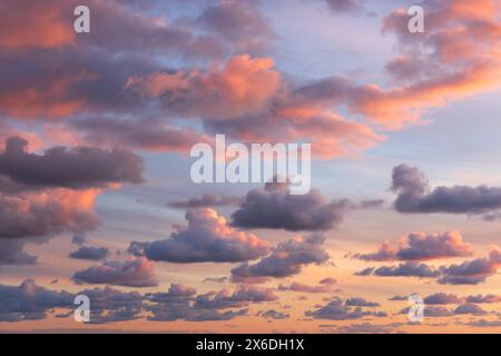 Small clouds in dramatic real sky at sunset texture background overlay. Dramatic blue, orange, and purple clouds. High resolution photograph perfect f Stock Photo