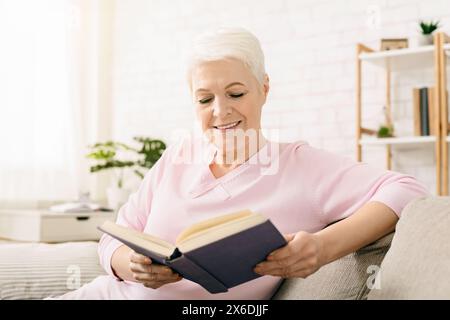 Woman Sitting on a Couch Reading a Book Stock Photo