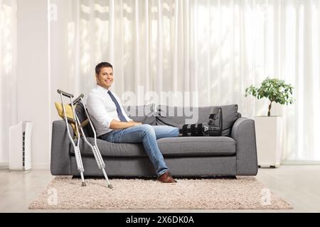 Man with a foot injury and leg brace sitting on a sofa at home Stock Photo