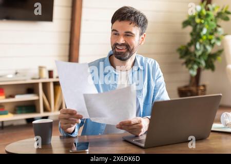 Man Sitting at Table Holding Piece of Paper Stock Photo