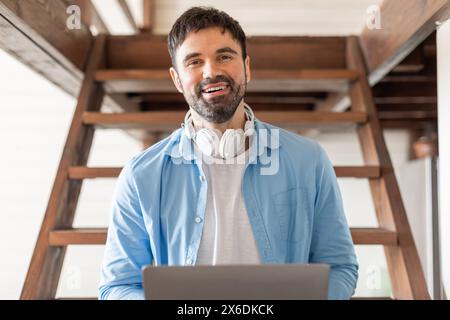 Man Wearing Headphones and Using Laptop, Sitting on Stairs Stock Photo