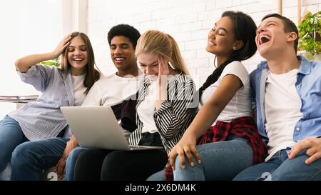 Group of Young Friends Laughing and Sharing Content on Laptop Stock Photo