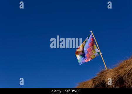 wiphala flag fluttering on a hut roof with a blue sky background at Jujuy, Argentina Stock Photo