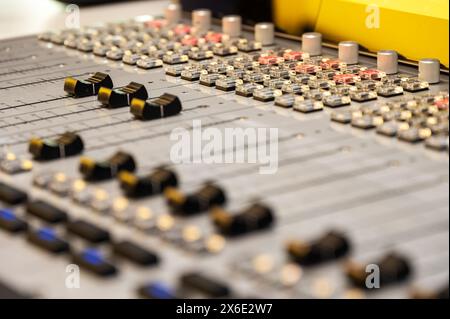 lose-up of a professional mixing console in a recording studio, featuring detailed sliders, knobs, and color-coded buttons. multimedia, music, podcast Stock Photo