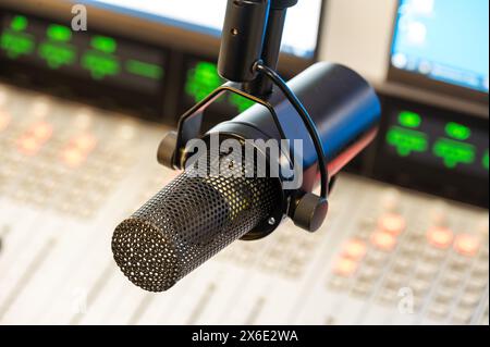 Professional microphone on radio studio, close-up view with mixing console in background, ideal for podcast recording and broadcasting Stock Photo