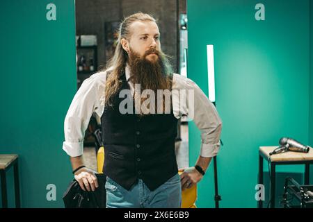 Man Bearded barber portrait .Male european young barber barber cheerful bearded long haired, standing with haircutting scissors in cookies and smiling Stock Photo