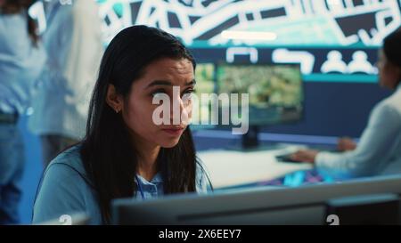 Indian employee monitoring traffic activity and communicating routes to delivery truck drivers, helping with express order shipment. Operator uses satellite navigation and CCTV. Camera A. Stock Photo