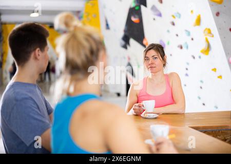 Woman chatting with friends at bar counter in climbing club during coffee break Stock Photo