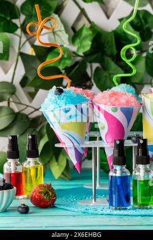 Snow cones with crazy straws on stands and flavoured syrups in front. Stock Photo