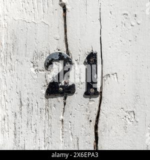 Number 21 attached to an old white painted cracked wood surface Stock Photo
