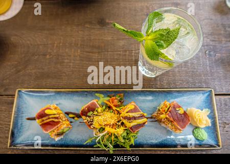 Overhead view of platter of sushi rolls. an appetizing roll on a blue rectangular ceramic plate is served on a table in a restaurant Stock Photo
