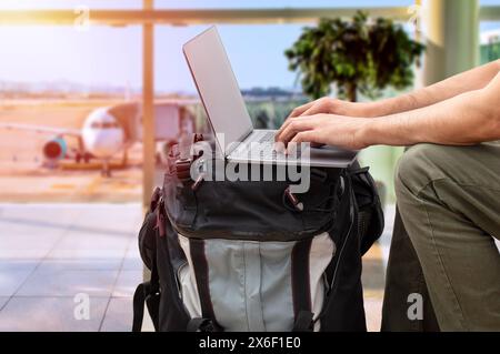 Cropped shot of an unrecognizable digital nomad sitting alone and typing on his laptop during the day at airport Stock Photo