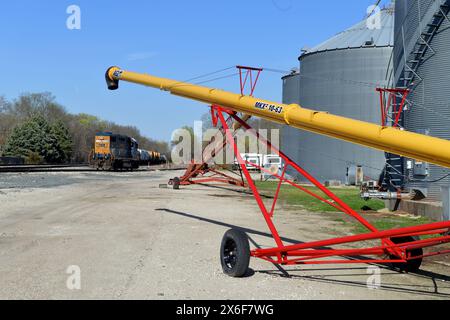 Seneca, Illinois, USA. A CSX Transportation locomotive idling on a siding next to metal silos and agricultural equipment. Stock Photo