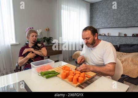 Mature russian husband and wife cooking pilaf together in the kitchen at home Stock Photo