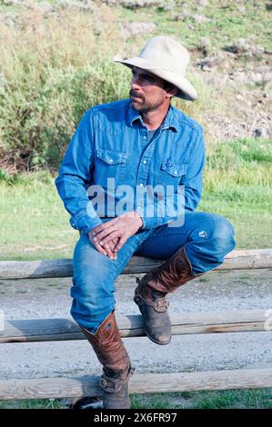 Montana cowboy sitting on fence (MR) Stock Photo