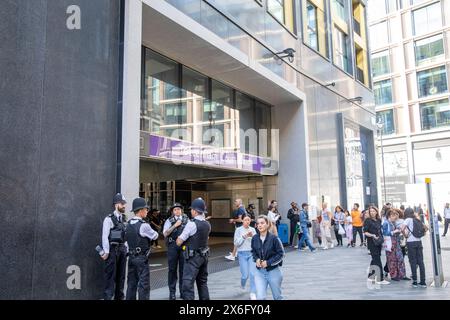 Metropolitan police stood outside Tottenham Court Road underground station, female officer has tattoo along right arm, central London,England,UK Stock Photo