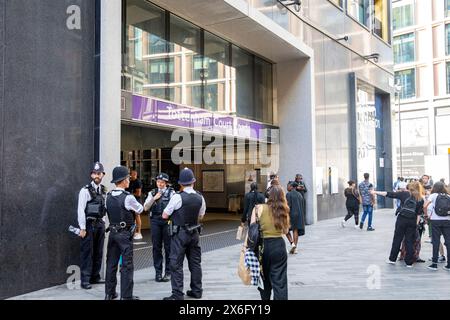 Metropolitan police stood outside Tottenham Court Road underground station, female officer has tattoo along right arm, central London,England,UK Stock Photo