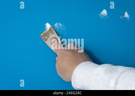 Small nail holes or deep scratches - filling up with putty plaster in the wall before painting Stock Photo