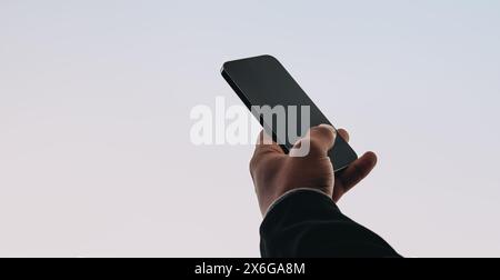 Male hand holds a modern smartphone displaying a social media message. The person is seen reading and texting, using a mobile app on the phone. The ba Stock Photo