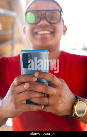 Glamorous smiling black man,using a social media app on a smartphone.Vertical Stock Photo