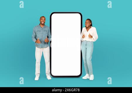 African American Young Couple Standing Beside a Giant Smartphone Stock Photo
