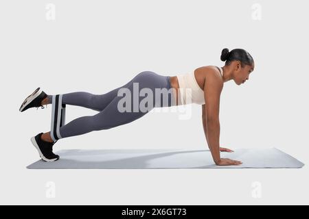 Woman Doing Push-Ups on Mat, Using Resistance Band Stock Photo