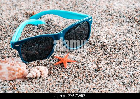 Blue sunglasses, starfish and seashell on beach Stock Photo