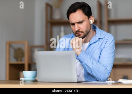 Focused Man Using Laptop for Work During Daytime in Office Stock Photo