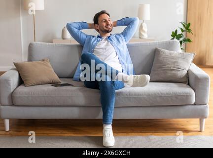 Man Sitting on Couch With Hands on Head Stock Photo