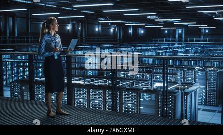 Data Center Female It Specialist Using Laptop. Server Farm Cloud Computing and Cyber Security Maintenance Administrator Running Diagnostics on Computer. Information Technology Professional. Stock Photo