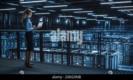 Data Center Female It Specialist Using Laptop. Server Farm Cloud Computing and Cyber Security Maintenance Administrator Running Diagnostics on Computer. Information Technology Professional. Stock Photo