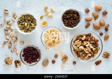 Top view, close-up, on a textured white concrete background, some bowls with mixed dried and dehydrated fruits Stock Photo
