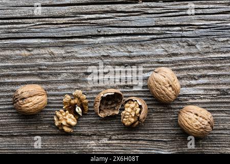 top view, on an old wooden board, in the foreground, some walnuts with and without shell. Copy space. Stock Photo