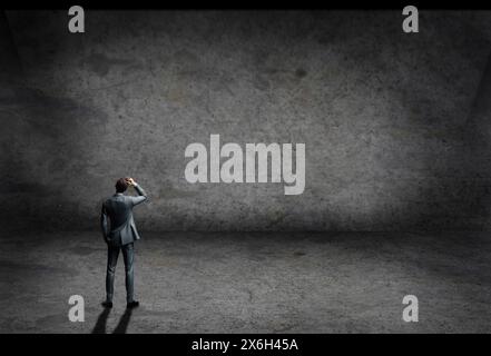 man in suit inside an empty room with concrete grey wall and floor Stock Photo