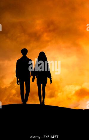couple hand in hand walking on a hill at sunset Stock Photo