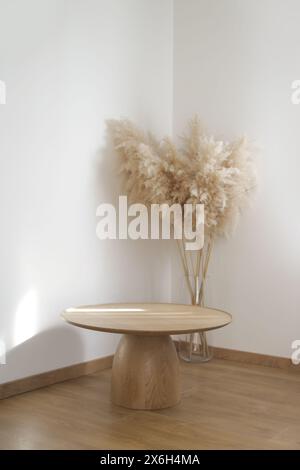 Round wooden coffee table and pampas grass in vase in the apartment, home decor concept. Stock Photo