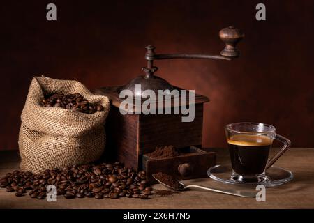 coffee beans in a jute bag, an old grinder and an espresso in a glass cup. Stock Photo
