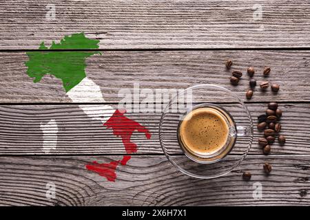 top view glass cup with espresso, some coffee beans and the shape of Italy with the colors of its flag on a gray textured wooden background. Stock Photo