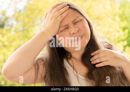 diseased mature woman experiences severe headache, holding head, Hot flashes during menopause, Decreased memory and concentration, exhausted, menopaus Stock Photo