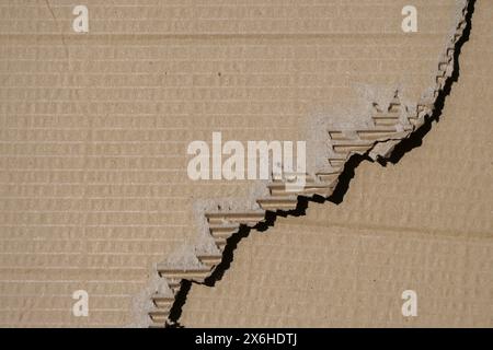 Old textured cardboard sheet with torn edges on brown cardboard texture background. Top view, copy space Stock Photo