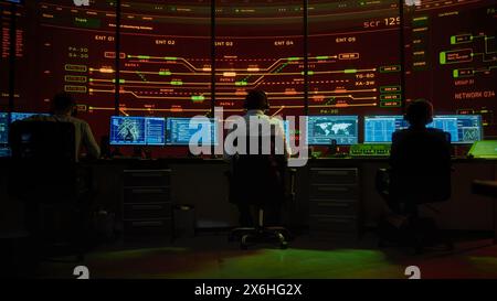 Professional IT Technical Support Specialists and Software Programmer Working on Computers in Monitoring Control Room with Digital Screens with Server Data, Blockchain Network and Surveillance Maps. Stock Photo