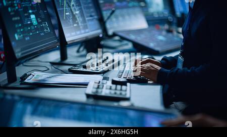 Close Up of a Professional Office Specialist Working on Desktop Computer in Modern Technological Monitoring Control Room with Digital Screens. Manager Typing on keyboard and Using Mouse. Stock Photo