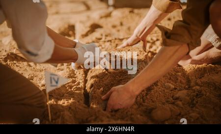 Archaeological Digging Site: Two Great Archeologists Work on Excavation Site, Carefully Cleaning, Lifting Newly Discovered Ancient Civilization Cultural Artifact, Historic Clay Tablet. Focus on Hands Stock Photo