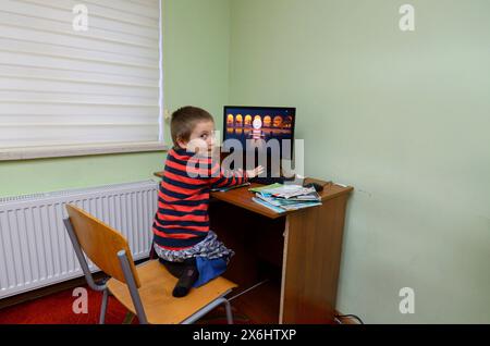 Computer room of the medrese. Little boy sitting in front a monitor of a computer. Islamic culture centre. October 21, 2018. Kiev, Ukraine Stock Photo