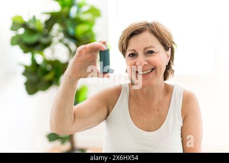 Elderly woman using asthma inhaler in clinic Stock Photo