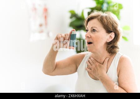 Elderly woman using asthma inhaler in clinic Stock Photo